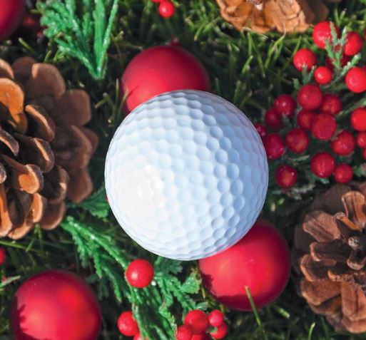 Weihnachtliches Dekobild mit einem Golfball in Nahaufnahme in einem Weihnachtskranz